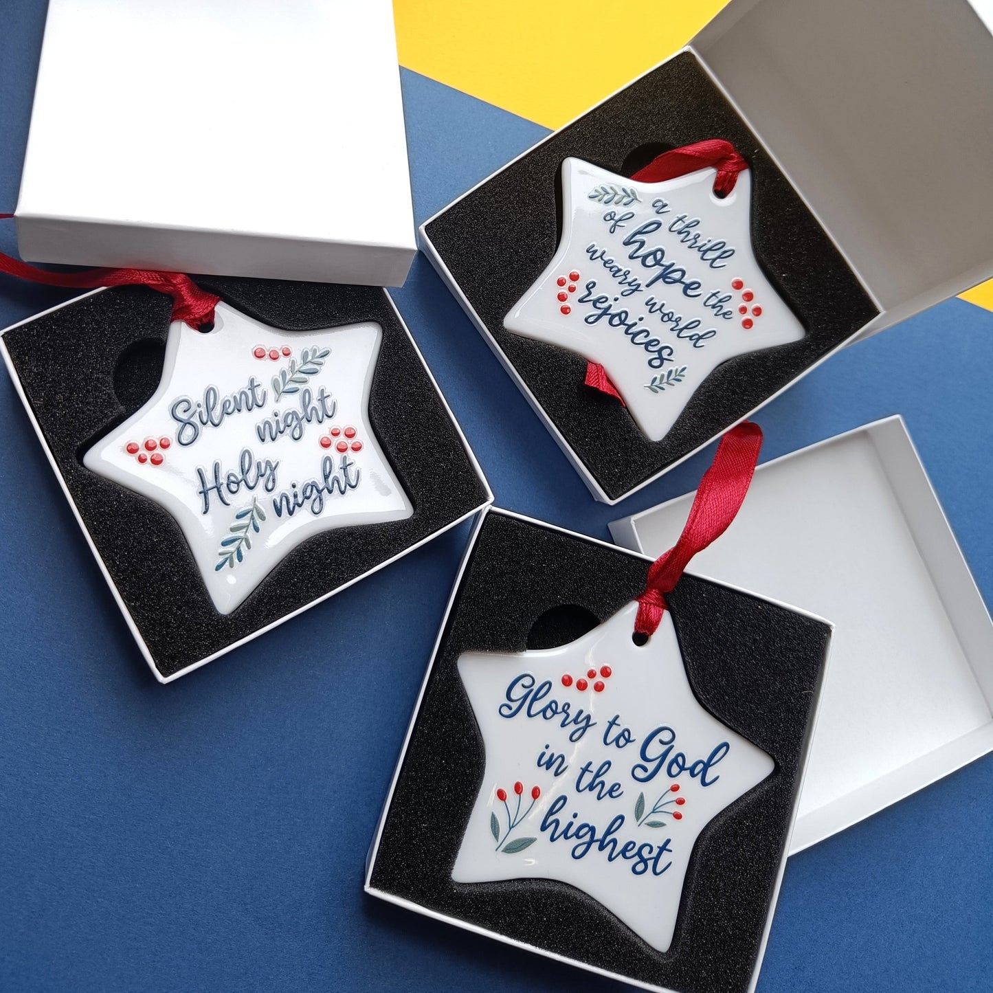 Star-shaped Christmas ornaments with religious text in gift boxes on a colorful background