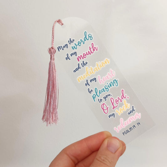 Decorative bookmark with colorful text and a pink tassel held against a light background