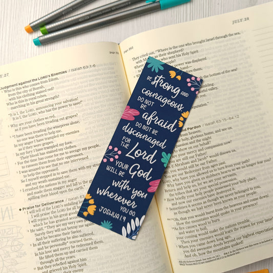 Open book with a colorful bookmark and pens on a light surface