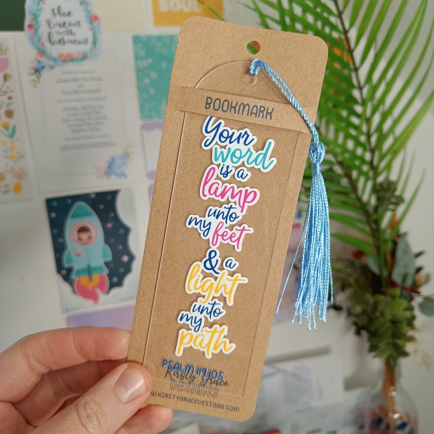 Bookmark with tassel held by a hand, with a colorful background