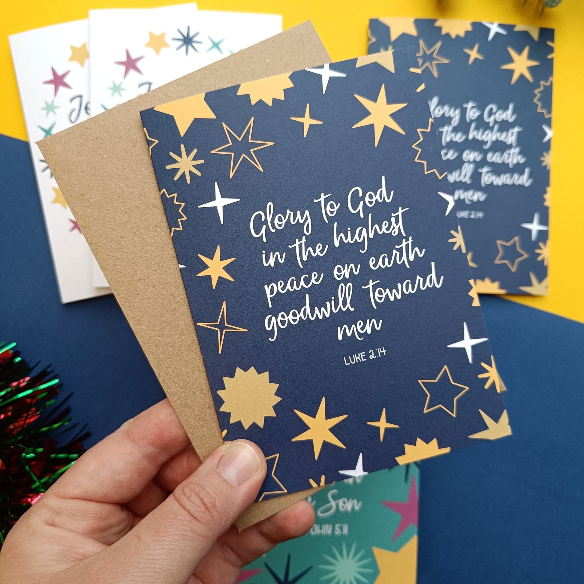 Hand holding a blue card with star designs and text, surrounded by other cards on a colorful background.