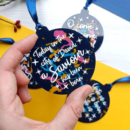Decorative metal tag held by a hand with colorful text on a yellow and blue background